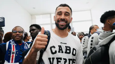 Thousands welcome home Cape Verde footballers after stunning World Cup run Michel Mvondo/BBC Pico Lopes smiles at the camera, wearing a white t-shirt emblazoned with the words "Cabo Verde"