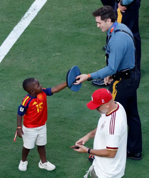 Reuters A smiling policeman hands the three-year-old his hat to try on