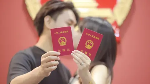 The lonely Chinese men being conned by fake brides Getty Images A newly-wed couple pose for a photo with their marriage certificates in Yangzhou, Jiangsu Province of China.