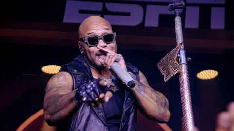 'Cancel it', Trump says after artists drop out of US Freedom 250 festival Getty Images A man wearing rhinestone-studded sunglasses sings into a rhinestone studded microphone while he points with his right hand