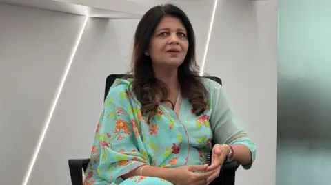 Instagram running ads promoting child sexual abuse material in India, BBC finds Shikha Goel is pictured inside the Cyber Security Bureau. She has long, dark hair and is wearing a bright green dress with flowers.