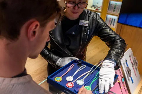 EPA A female shop assistant at a Swatch store shows a blue box with eight Royal Pop pocket watches of different designs to a man.