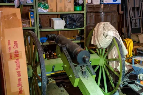 Ex-Canada MP arrested after police seize 439 guns and antique cannon from his home RCMP An antique cannon is seen in a storage area with shelving units and other boxes and miscellaneous items in a home in Dauphin, Manitoba.