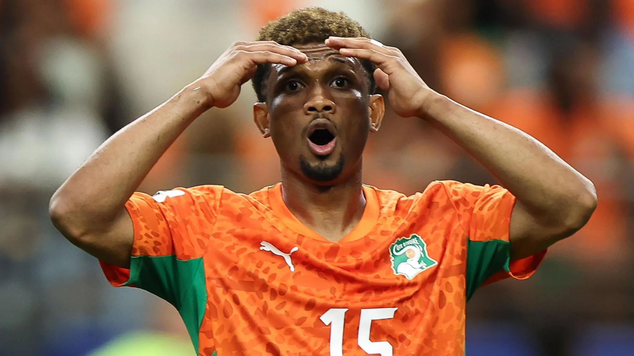 Amad Diallo, visible from chest up, holds is hands to his head in disbelief as he stares forward with his mouth wide open in an O-shape and a look of surprise on his face