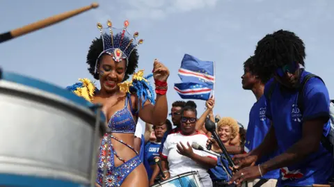 Thousands welcome home Cape Verde footballers after stunning World Cup run Reuters A lady in a blue, red and white carnival outfit dances amongst a crowd