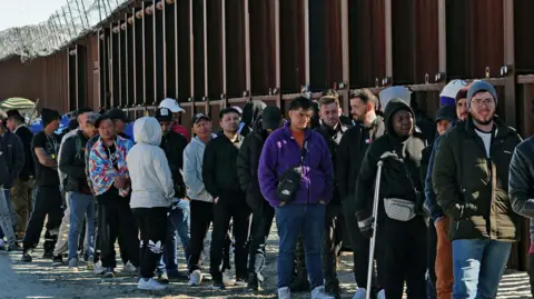 Getty Images A long line of migrants at the US-Mexico border in 2023