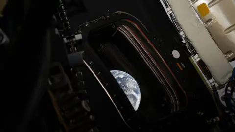 Nasa/Reid Wiseman An image from inside of the Orion capsule, which shows a small window and part of the Earth outside