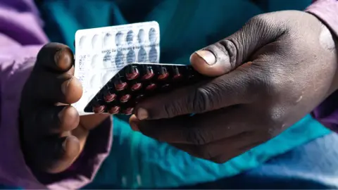 AFP via Getty Images The hand of an HIV positive patient in Zimbabwe holding a packet of tablets received as part of his treatment in Harare - June 2019.