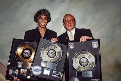 Clive Davis, music mogul behind Whitney Houston and Bruce Springsteen, dies aged 94 Getty Images Whitney Houston and Clive Davis hold up a collection of gold and platinum records, celebrating the success of her album I'm Your Baby Tonight