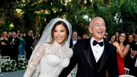 Instagram/Reuters Lauren Sánchez wears a Dolce & Gabbana haute couture gown while Jeff Bezos places his arm around her while wearing a smart black tuxedo 
