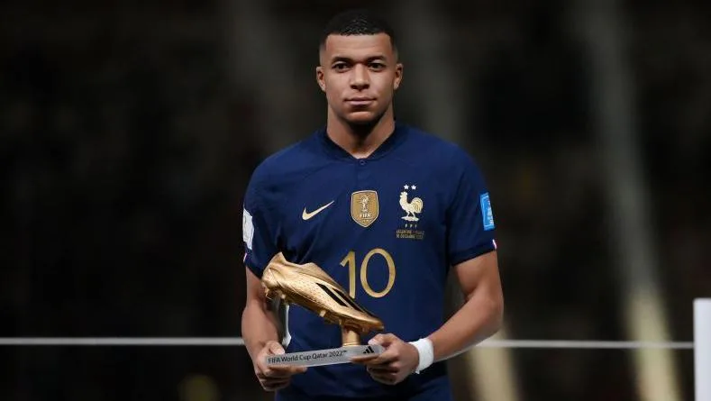 Kylian Mbappe holding the 2022 World Cup Golden Boot trophy