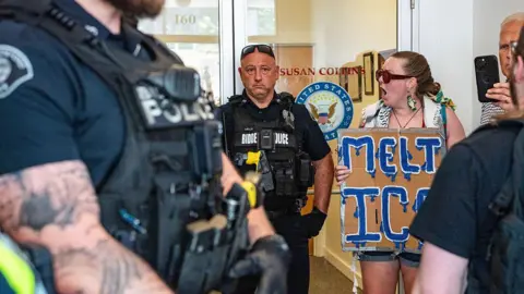 Getty Images Protesters outside Susan Collins office, seen next to police.