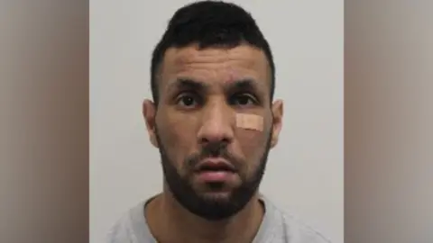 Pub thief jailed over £2.2m Fabergé theft Met Police A head‑and‑shoulders image of a man looking at the camera, with short dark hair, facial hair and a small bandage beneath one eye, set against a plain background.