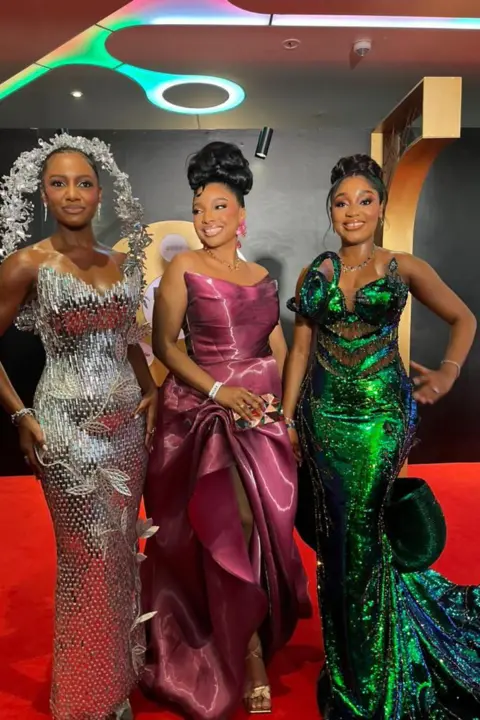 Dress made from 500 loaves stuns Africa Magic Viewers' Choice Awards BBC/CHIMEZIE UCHEAGBO Three women pose in their dresses.