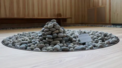 Reuters Pebble artwork in Oslo memorial for 2011 massacre victims - a pile of pebbles in a circular space inside a room