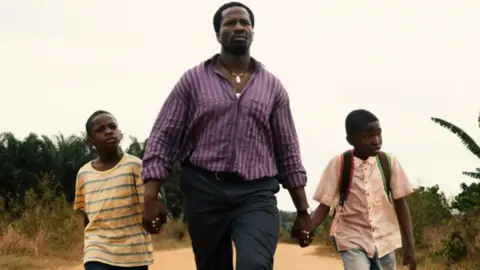 Dress made from 500 loaves stuns Africa Magic Viewers' Choice Awards MUBI An actor is walking, holding the hands of two children, in the film