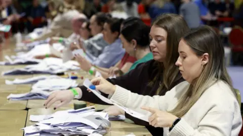 Social Democrats' Ennis elected in Dublin Central by-election PA Media A woman in a cream jumper, with brown hair, looks at a white ballot paper , there is a woman with dark hair and a dark jumper beside her.