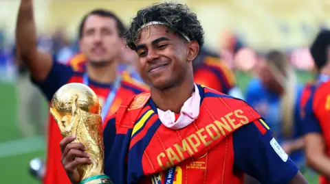 Reuters Spain's Lamine Yamal smiles as he celebrates with the World Cup trophy after winning the World Cup