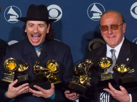 Clive Davis, music mogul behind Whitney Houston and Bruce Springsteen, dies aged 94 Getty Images Clive Davis and Santana celebrate their success at the 2000 Grammy Awards, they are both wearing black suits and holding several Grammy trophies each.
