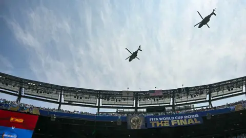 Getty Images Marine One, carrying US President Donald Trump, flies over the stadium ahead of the 2026 World Cup football tournament final match between Spain and Argentina at the New York/New Jersey Stadium in East Rutherford on July 19, 2026

