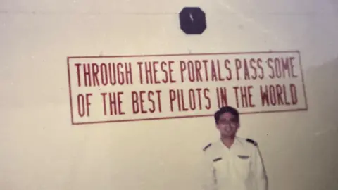 Capt Sumeet Sabharwal's family Capt Sumeet Sabharwal's stands next to a white wall as a young pilot