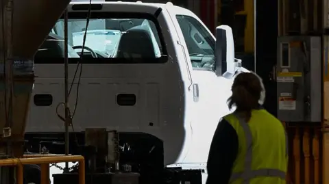 Ford rehires human engineers after AI fails to match quality checks Bloomberg via Getty Images A Ford truck on a production line, passing through inspection checks, at a plant in Ohio. A female worker wearing a high-vis jacket looks on.