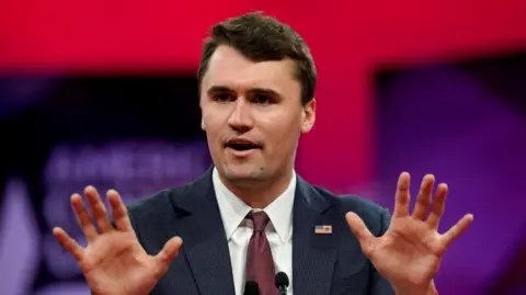 Reuters A man gestures with his hands as he talks in front of a red and purple background