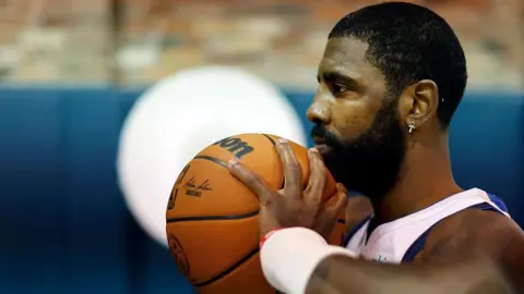 Getty Images Kyrie Irving holding a Wilson-branded basketball to his chin.