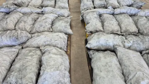 UK actress charged with importing meth worth almost A$300m into Australia Australian Federal Police/Australian Border Force Large filled white bags, flecked with black, laid on the ground