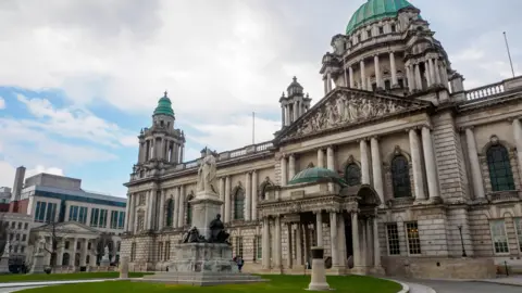 Why are so many organisations leaving X? Getty Images A stock image showing the exterior of Belfast City Hall during the day. It is an ornate grey building with copper green tower domes.