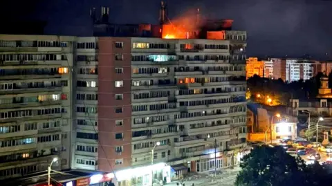 DSU via Reuters A small fire is seen on top of a multi-storey building at night in Galați, Romania on Friday.