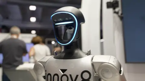 AI will create more jobs for humans, not replace them, Amazon founder Bezos says Close up of a humanoid robot with a black head with a blue light around it