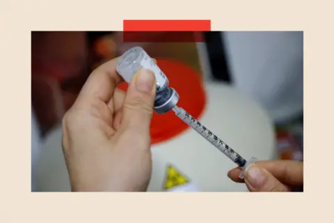 Reuters The hands of a nurse prepare a Botox injection by drawing liquid from a container using a syringe. In the background is a much larger container and a triangular yellow and black toxic sign appears out of focus.