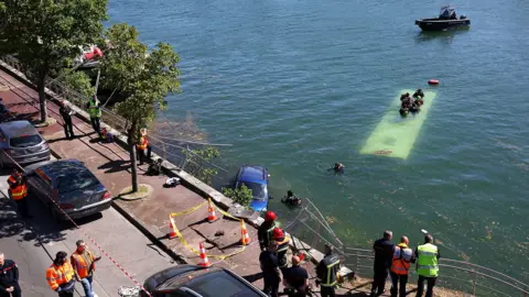 Trainee driver crashes bus into River Seine Reuters A view of the bus under water from the street, where several people in high-vis jackets are stood and cordons and traffic cones have been set out.