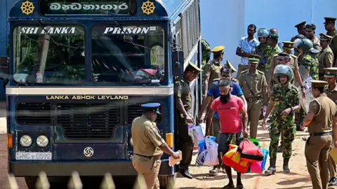 Sri Lanka prison riots leave 26 dead and more than 100 injured Getty Images Prisoners being escorted to a blue bus which bears the words Sri Lanka Prison - one man wears a red T-shirt and carries bags. Military officers can be seen around the bus