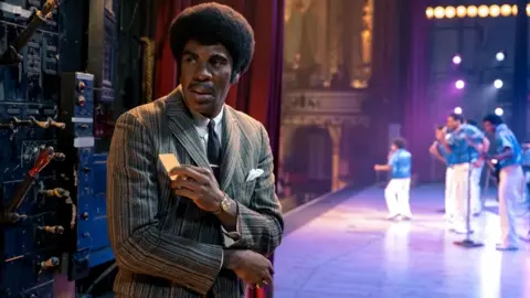 Universal Colman Domingo as Joe Jackson, seen at the side of a stage while the Jackson 5 perform, in the musical biopic Michael