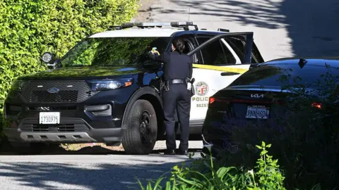 Rihanna's Beverly Hills home hit by gunfire, police say Getty Images/DUTCH/Bauer-Griffin/Contributor A police vehicle is parked on a road with an officer standing next to it