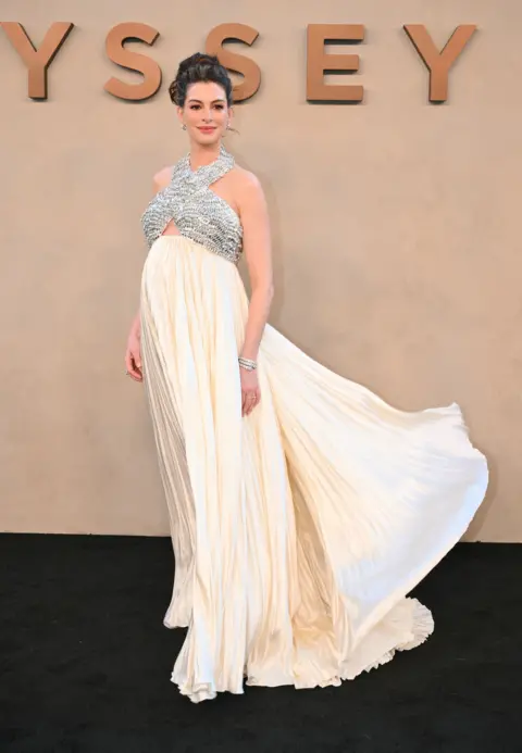 Anne Hathaway pokes fun at 'fake baby bump' theories Getty Images Anne Hathaway in a flowing cream gown at The Odyssey premiere in New York