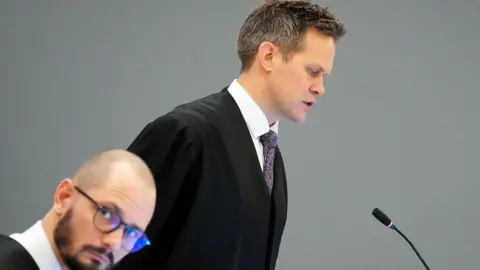 Norway braces for verdict in rape trial of crown princess's son Høiby AFP via Getty Images A man in a gown and tie speaks in front of a microphone