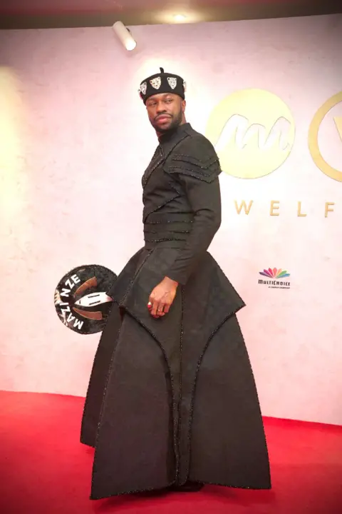 Dress made from 500 loaves stuns Africa Magic Viewers' Choice Awards BBC/GIFT UFUOMA Nigerian actor Stan Nze is styled in a black apparel and carried his signature tradtional engraved hand fan made with horse skin.
