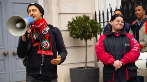 IWGB UK trade union boss Alex Marshall, left, holding a megaphone at a street protest