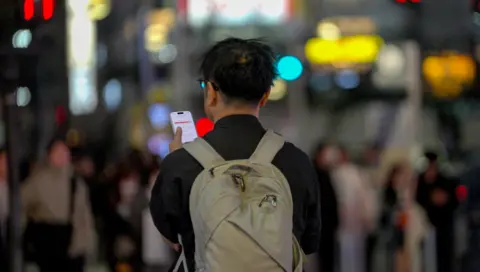 Man holding phone in busy street