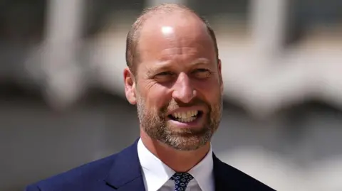 Getty Images Prince William in a navy suit and white shirt smiles 