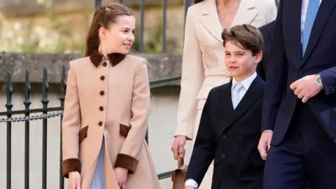 PA Media Princess Charlotte and Prince Louis walk and smile as Charlotte looks at her brother who looks ahead