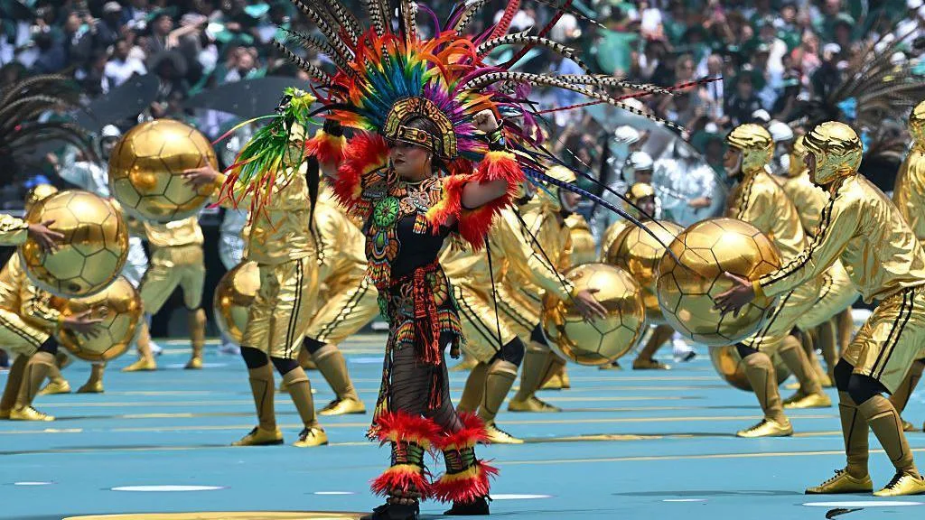 A performer wears a colourful costume amid a host of entertainers dressed in gold at the opening ceremony