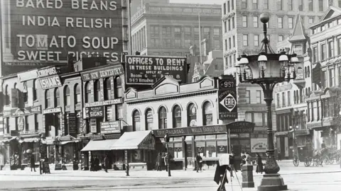 Would you pay $58.5m to live in this iconic New York building? Getty Images Historic black and white photo showing an ornate streetlamp in front of buildings and old billboards