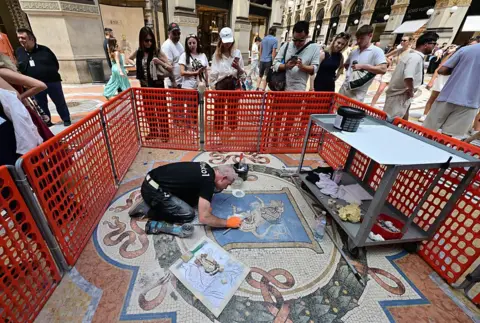 Italy restores lucky testicles on bull mosaic worn down by tourists Stefano Rellandini/AFP via Getty Images Restorer Gianluca Galli works on the mosaic of the bull during the restoration in the Galleria Vittorio Emanuele II, in Milan on 28 May 2026.