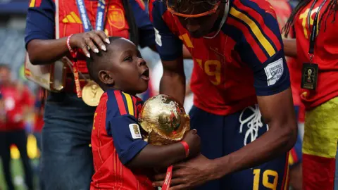 Fifa/Getty Images Keyne holds the World Cup trophy supported by his older brother