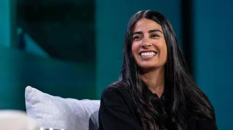 Xbox workers stunned after jobs 'bloodbath' Getty Images A woman with long dark hair sits on a sofa on-stage at a business event. She looks relaxed as she smiles at the host off-camera.
