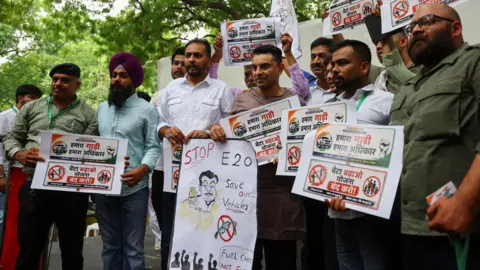 Reuters Tehseen Poonawalla, a New Delhi-based socialite and supporter of India's Congress party, holds a poster as he and others take part in a protest against the Centre's rollout of the E20 ethanol fuel-blending policy at Jantar Mantar in New Delhi, India, July 5, 2026. REUTERS/Anushree Fadnavis